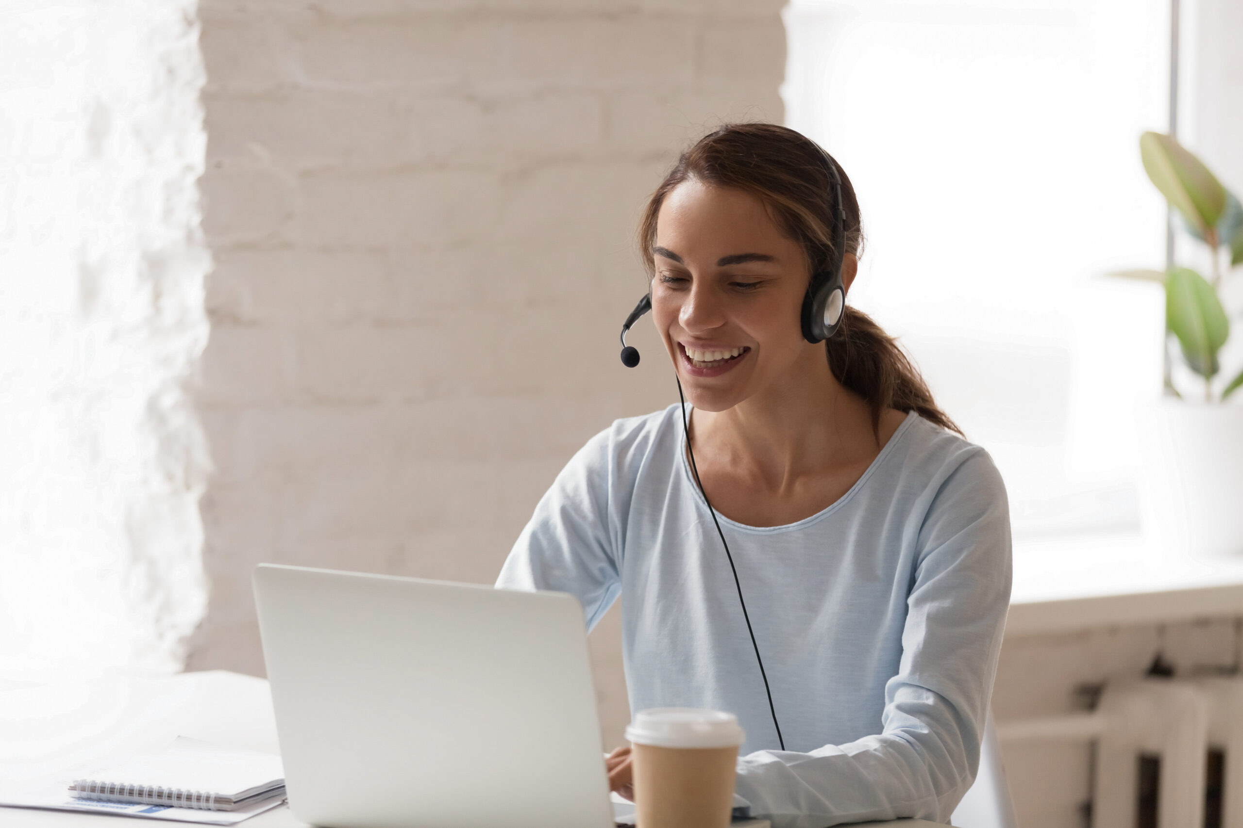 Beautiful smiling woman working in headphones at office. Call center introduction. Happy employee at workplace. People at work at home. Video job interview, language course, class concept